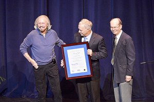 Singer-songwriter-producer Barry Gibb, left, laughs at an audience member's comment Monday night at MTSU during his recognition as the inaugural fellow of The Center for Popular Music in the university's College of Mass Communication. Presenting Gibb with documentation of his honor inside Tucker Theatre are Mass Comm Dean Ken Paulson, center, and Dr. Dale Cockrell, director of the Center. (MTSU photo by Andy Heidt)